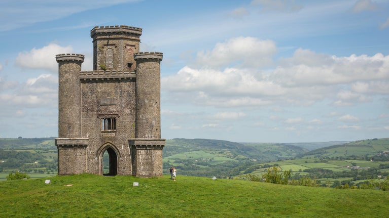 A couple in the distance walking past Paxton's Tower in spring, Carmarthenshire